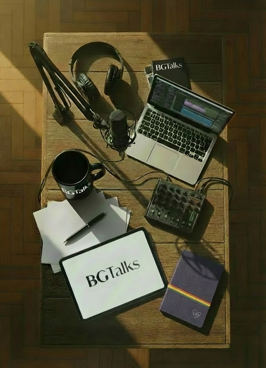 Collage visto dall’alto su tavolo di legno: libri sovrapposti con qualche foglio e penna, due vinili che si incrociano parzialmente, alcune custodie di DVD, un microfono da podcast e una videocamera appoggiati in modo naturale, composizione leggermente disordinata ma armonica, luce calda e accogliente, stile fotografico realistico